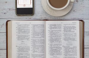 Tablescape of an open Bible, smart phone and hot drink