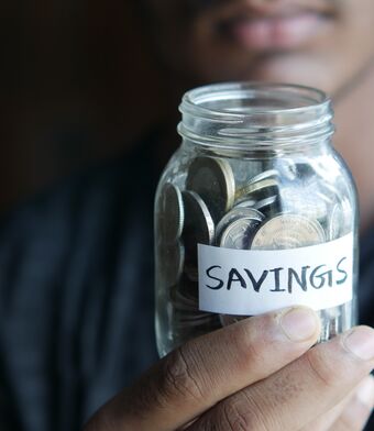 Man holding a jar of pennies with a 'savings' label on it