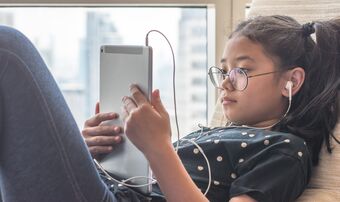 Girl on ipad with headphones in