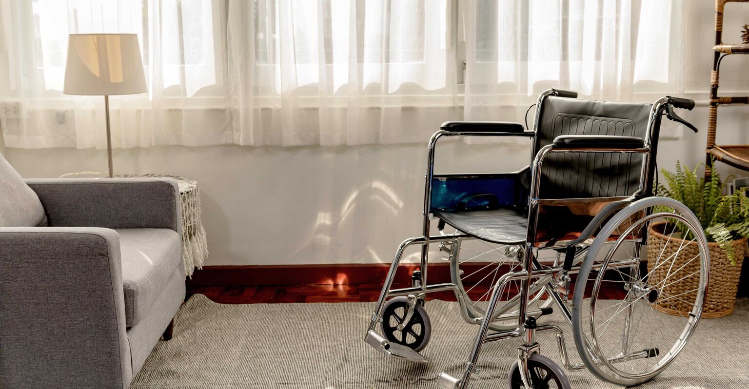 Empty wheelchair by hospital sofa