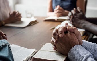 Prayer group bibles hands