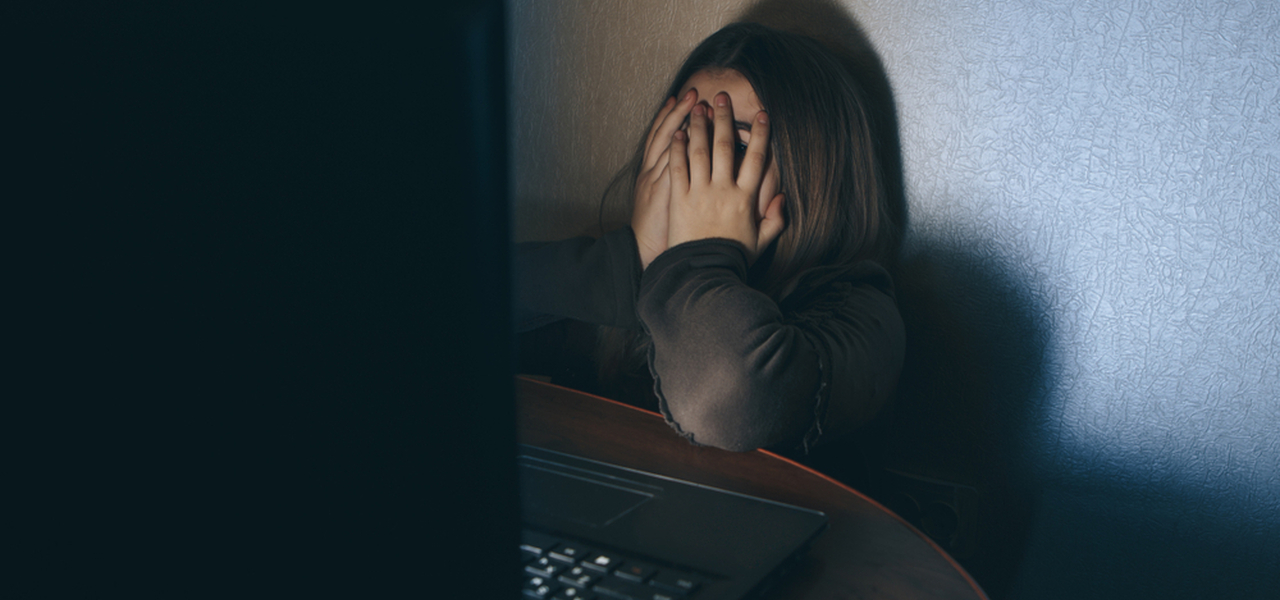 Teenager on computer dark embarrased covering face